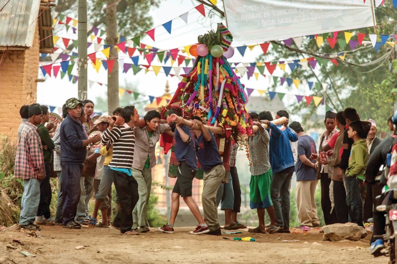 Men carrying large, festive cone on poles